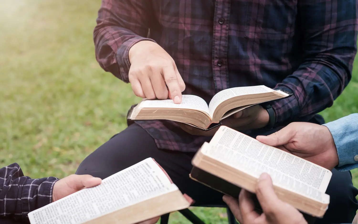 Christliches Lebensbibelstudienkonzept Eine Gruppe christlicher Freunde sitzt zusammen und studiert draußen im Park die Bibel